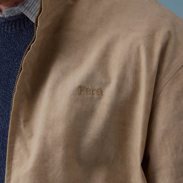 Close-up of a brown jacket with 'Fera' branding on a blue background