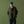 Load image into Gallery viewer, A man stands against an olive green studio backdrop wearing an olive green utility jacket over a dark navy sweater and white collared shirt, with dark blue jeans, brown boots, and a blue baseball cap.
