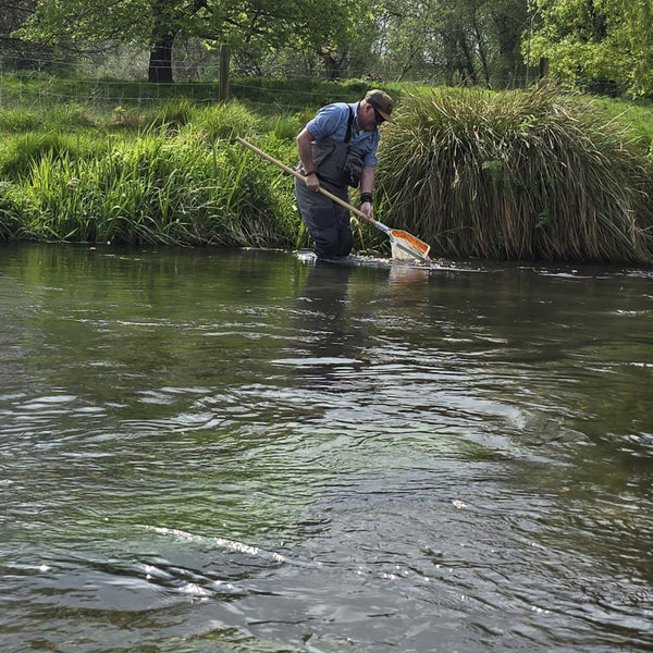 man wading with fishing net in river