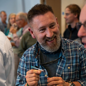 man smiling wearing checkered shirt