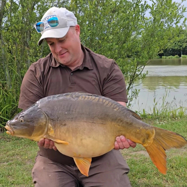 man holding large fish on the side of riverbank