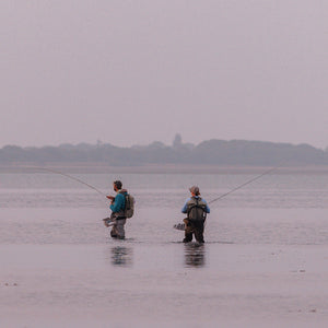 tow people in waders fishing in a river