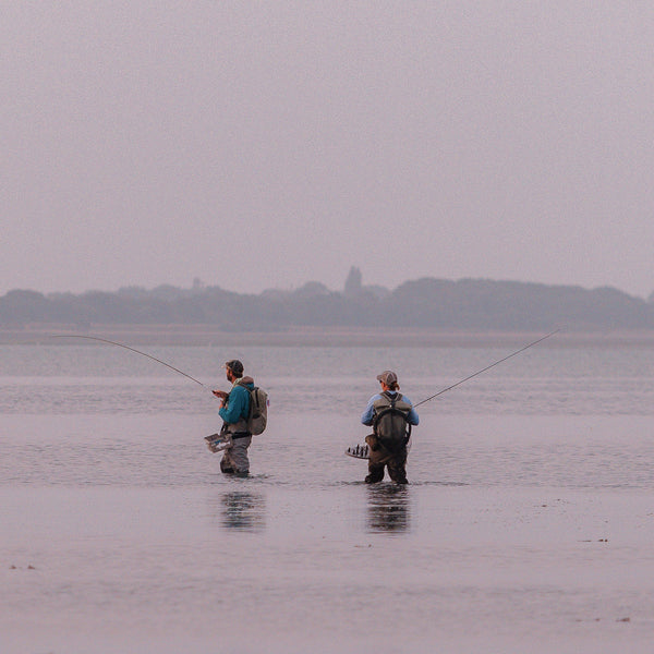 tow people in waders fishing in a river