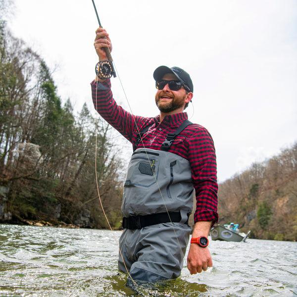 Man waist deep in a river, wearing Mens Pro Waders and a red checkered shirt